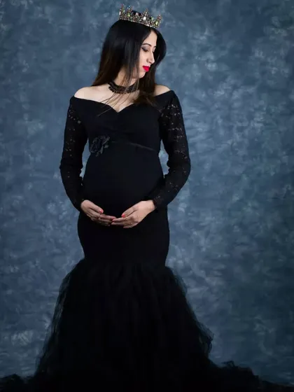 Embrace your inner queen with a regal and elegant portrait. This shot features one of our classic black mermaid gowns and a crown, set against a timeless mottled backdrop to create a sophisticated and powerful maternity photograph.