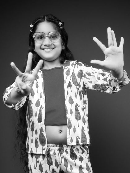 This black and white portrait captures the confidence of a stylish eight-year-old. Holding up her fingers to show her age, her bright smile and cool glasses make for a modern and fun birthday photo that’s full of personality.