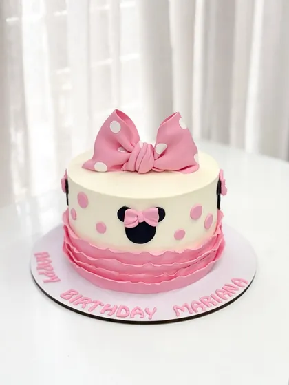 A sweet and classic Minnie Mouse cake for Mariana's birthday. The design features Minnie's iconic silhouette, a big pink bow, and pretty pink ruffles.