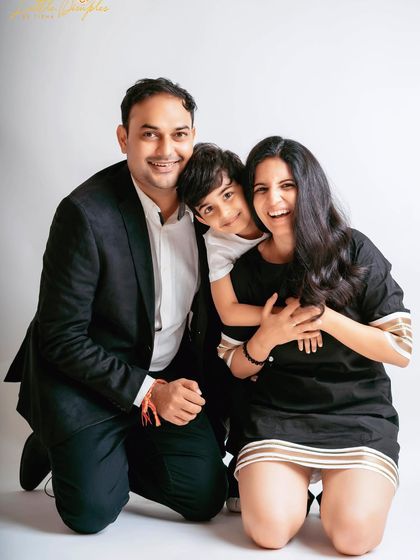 A joyful and candid moment from a studio family photoshoot. The son's happy hug from behind perfectly captures the playful spirit of this family.