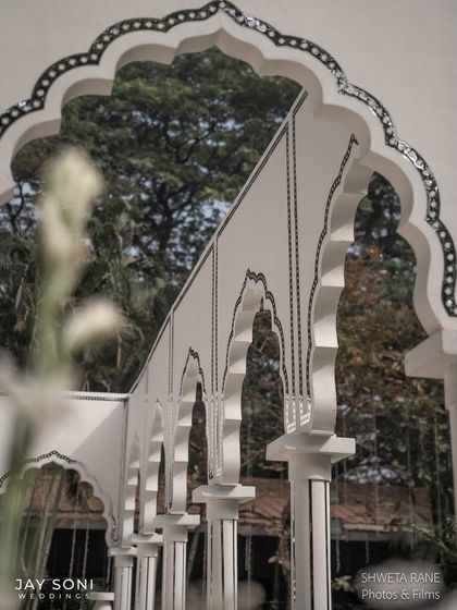 Beautiful ivory-toned lounge decor with stunning architectural details. The intricate mirror work on the arches adds a touch of Rajasthani-inspired elegance to the serene setting.