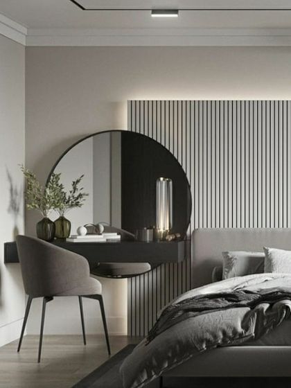 A beautifully minimalist and functional vanity area within a bedroom. The floating dressing table with a large circular mirror is set against a backdrop of vertical wall paneling and soft backlighting. This design creates a chic and tranquil corner that is both practical and elegant.