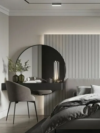 A beautifully minimalist and functional vanity area within a bedroom. The floating dressing table with a large circular mirror is set against a backdrop of vertical wall paneling and soft backlighting. This design creates a chic and tranquil corner that is both practical and elegant.