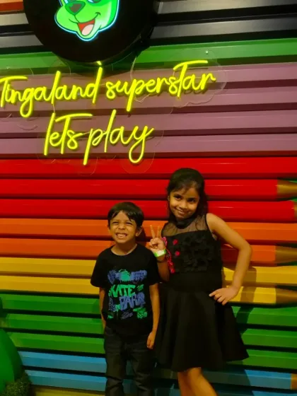 A brother and sister pose in front of our "Tingaland Superstar" sign, ready to play.