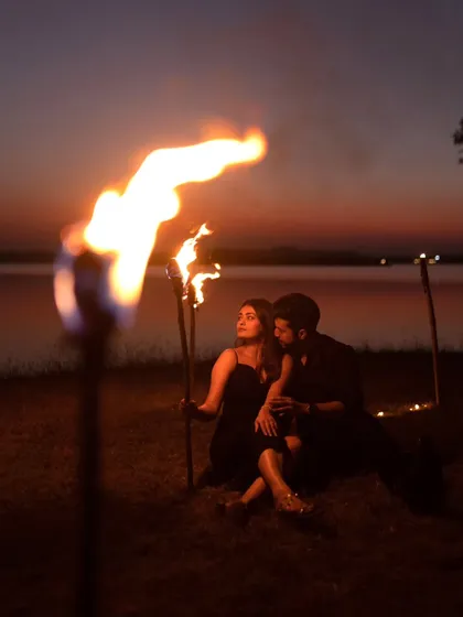 Creating a dramatic and romantic atmosphere with fire torches during a sunset pre-wedding shoot by the lake. This is for couples who want bold, unforgettable images.