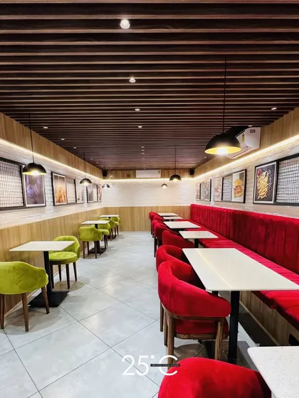 We design cafe interiors that are both stylish and functional, creating a distinct brand atmosphere. This project showcases a strategic layout with a mix of plush velvet booth seating in bold red and comfortable lime green chairs, creating visual interest and optimizing the flow for both patrons and staff.