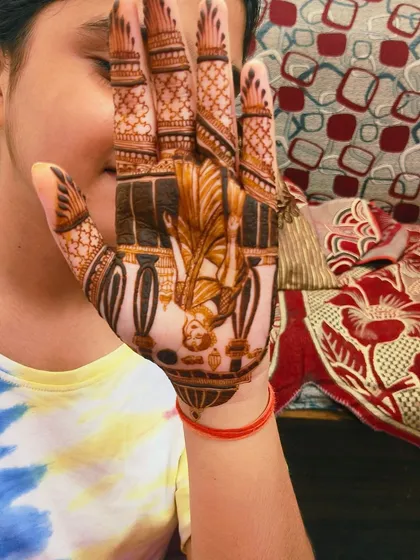 Another angle of the Karva Chauth mehandi on a young client, showing the detailed portrait work on the palm.