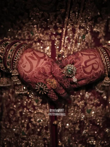 A moody, artistic shot of the bride's hands, showcasing the dark henna stain and personalized initials.