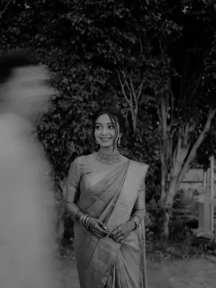 An artistic black and white bridal portrait with a sense of movement and mystery, created by a blurred figure in the foreground.