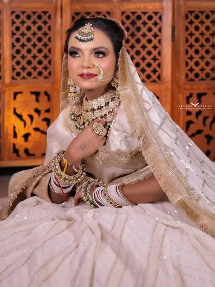 A relaxed seated pose, capturing the bride's graceful posture and the intricate details of her outfit.