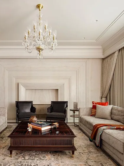 In this living room, we integrated the fireplace with a continuous expanse of white Ondulutu stone, creating a seamless and monumental feature wall. The neutral palette is punctuated by luxurious textures and carefully selected furniture, achieving a balance of classic grace and contemporary comfort.