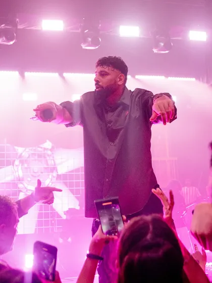 We curate and manage top talent to match the energy of your event. Here, a headline artist engages with the crowd, creating an unforgettable concert atmosphere during a grand Sangeet celebration.