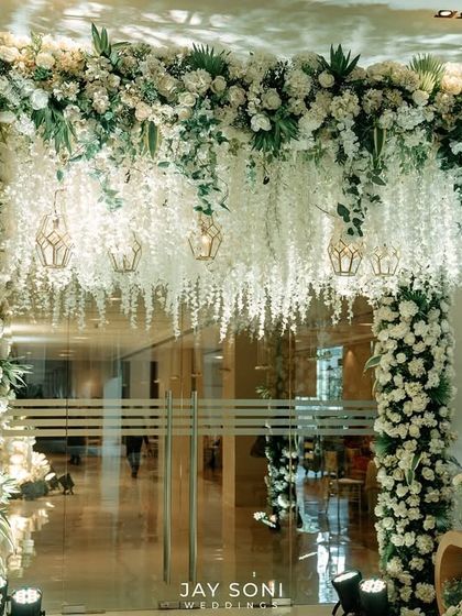 Another angle of the magnificent floral entrance arch, showcasing its fullness and the seamless integration of greenery and white blooms to create a truly immersive experience.