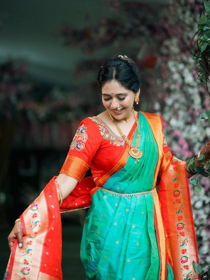 A bride looking down at her beautiful Nauwari saree with a gentle smile.