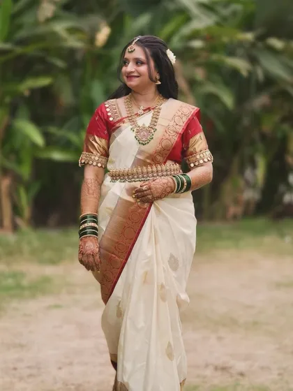 A full-length shot of the bride in her beautiful white and red South Indian saree, perfect for a temple wedding.