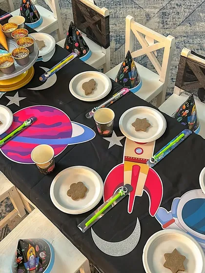 The kids' dining table at the space party, with themed plates, cups, and a custom table runner.