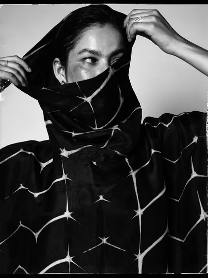 An expressive black and white shot where the model interacts with the fabric. The composition is dynamic and modern.
