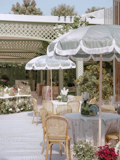 This elegant spring luncheon showcases our expertise in creating sophisticated daytime events. The open-air setting features chic fringed parasols, cane-back chairs, and floral-print tablecloths, all contributing to a light and airy garden party atmosphere.