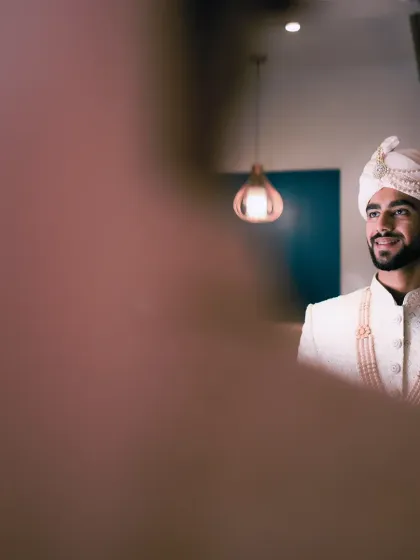A groom's final look in the mirror before he meets his bride. This candid shot captures a moment of quiet confidence and anticipation, a classic portrait for any groom on his wedding day.