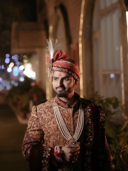 A candid shot of Akhilesh, looking away with a gentle smile, the bokeh lights in the background adding a festive touch.
