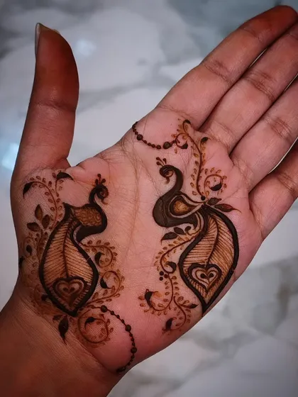 A simple yet charming example of my minimalist henna art. This design features two small, elegant peacocks on the palm, connected by a delicate beaded chain, perfect for someone who wants a touch of tradition without full coverage.
