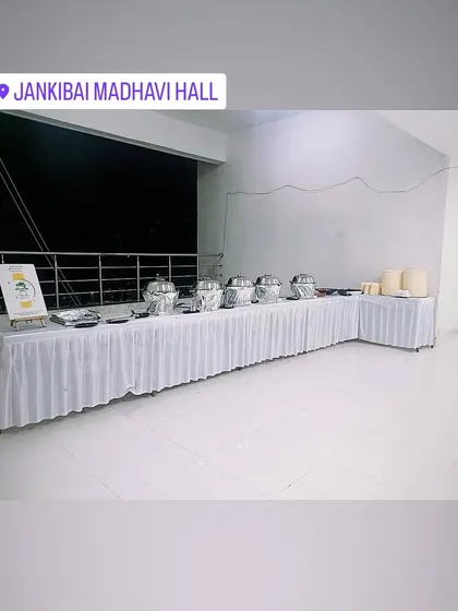 A wide angle of the white buffet setup at Jankibai Madhavi Hall, showing the full length of the serving area.