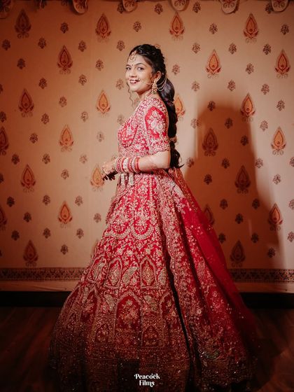 A full-length portrait of the bride, her red lehenga twirling around her. This shot captures her playful spirit and the beauty of her wedding attire.