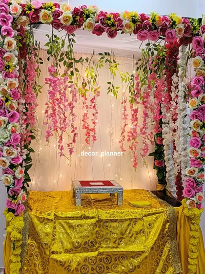 This Ganpati mandap features a canopy of pink and yellow flowers with hanging floral strings. The golden cloth on the base adds a touch of royalty to the entire setup.