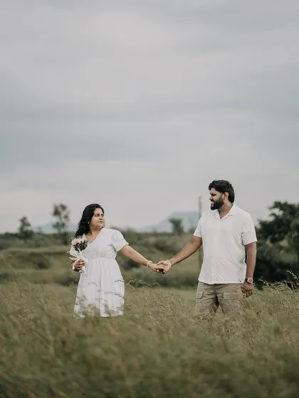 A candid shot of the couple walking hand-in-hand through a tall grassy field, feeling natural and relaxed.