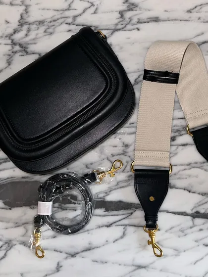 The black Noble bag with its two strap options. The contrast between the black leather and the off-white fabric strap creates a very modern and stylish look.