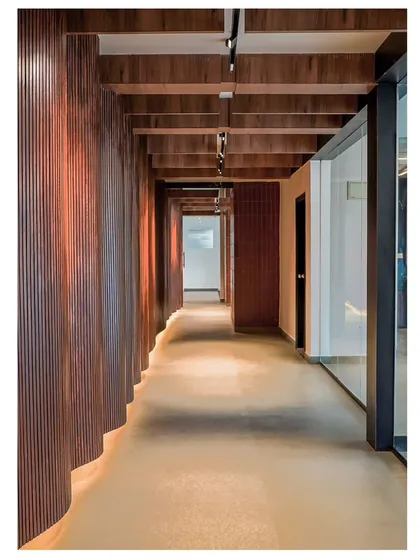 For the Marquise Clubhouse, we designed a fluid corridor with curved wooden walls to guide movement and create visual interest. This architectural feature transforms a simple passageway into a dynamic and engaging spatial experience, showcasing our work in commercial interior design.