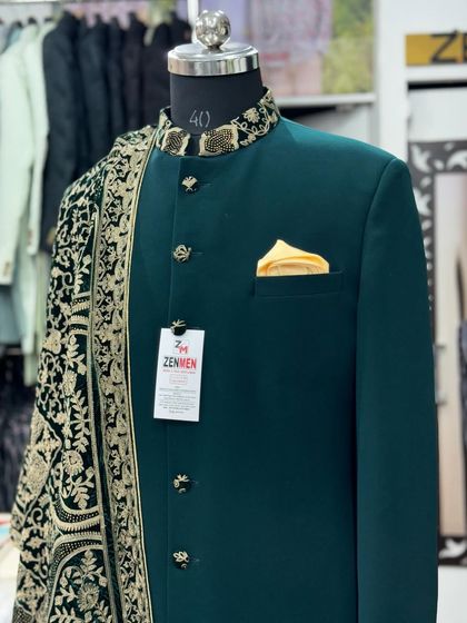 A close-up of the hand-embroidered collar on the green sherwani. The intricate gold detailing provides a luxurious contrast against the deep green fabric, highlighting the craftsmanship.