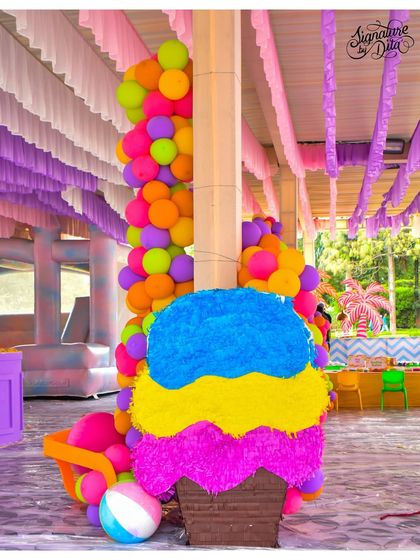 This giant ice cream cone piñata, surrounded by colourful balloons, was both a fun activity and a fantastic piece of decor for the summer carnival party.