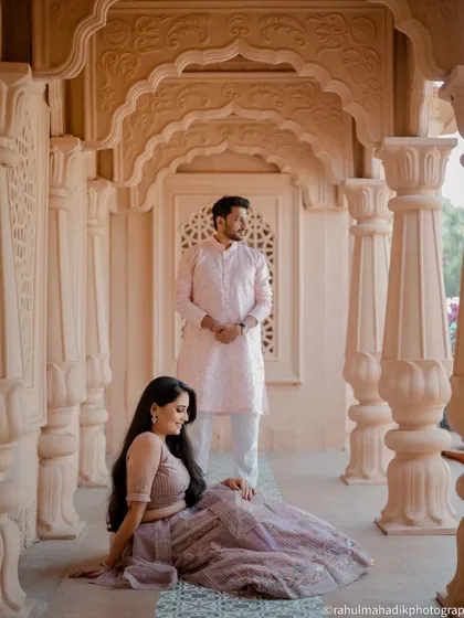 A regal portrait set within a corridor of ornate arches. The composition uses the architecture to create leading lines and a sense of grandeur, perfectly complementing the couple's elegant attire.