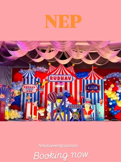 A wide view of the detailed carnival stage setup, showcasing multiple themed props like a life-sized giraffe, circus signs, and colorful balloon arrangements.