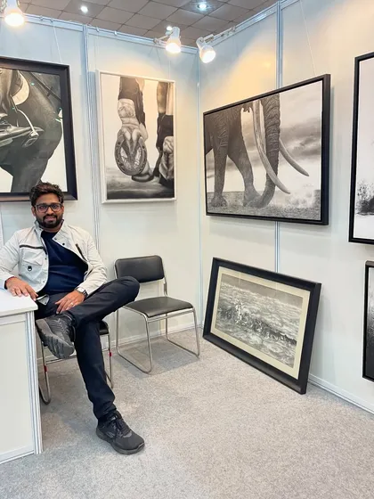 Taking a moment to relax in my exhibition booth, surrounded by my large-scale charcoal pieces of elephants and horses.