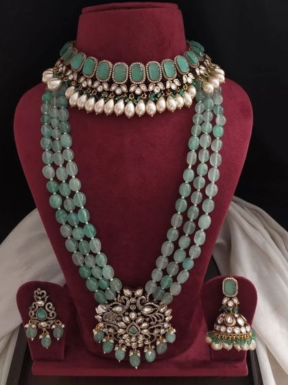 A variation of the green Victorian set, this one features a choker with oval green stones and pearl drops, paired with a long beaded necklace.