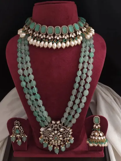 A variation of the green Victorian set, this one features a choker with oval green stones and pearl drops, paired with a long beaded necklace.