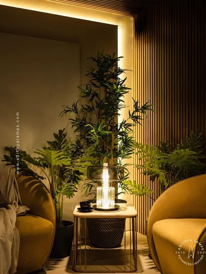 This image showcases the table lamp's warm light against a backdrop of wood paneling and plants, creating a rich, layered, and inviting atmosphere.
