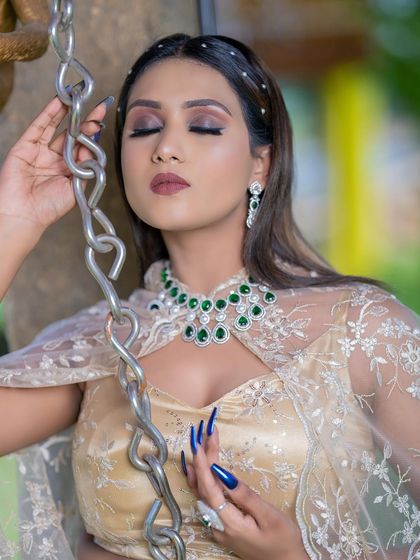 A modern and chic Indo-Western rental outfit, featuring a golden crop top and skirt with a sheer, embroidered cape. The emerald necklace adds a pop of colour.