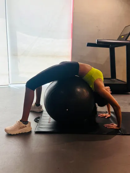 Using props like the stability ball adds a new level of challenge to your workout. This backbend, or wheel pose, on the ball deeply stretches the spine and shoulders while requiring significant core control to stay balanced.