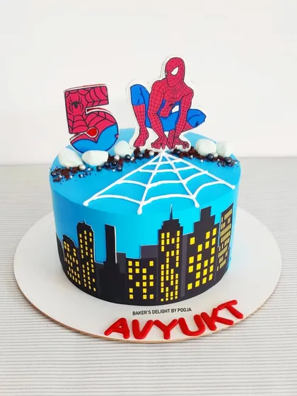A cake for a little superhero's fifth birthday. This Spider-Man design features the iconic hero perched above a city skyline, with a piped spiderweb and bold colors to capture the action.