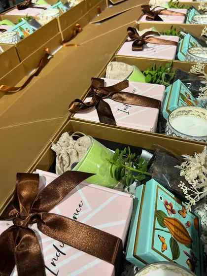 A top-down view of the corporate wellness hampers, showing the careful placement of each item. The brown ribbon adds a touch of earthy elegance to the pink and gold boxes.