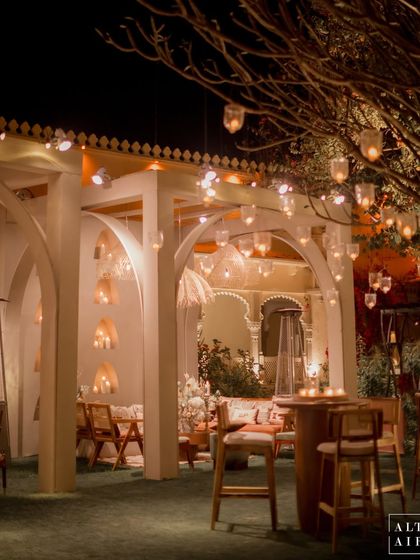 An outdoor bar and lounge area at the 'Muted Melodies' sangeet. The modern white arches and hanging glass lanterns created an ethereal and inviting space for guests to mingle.