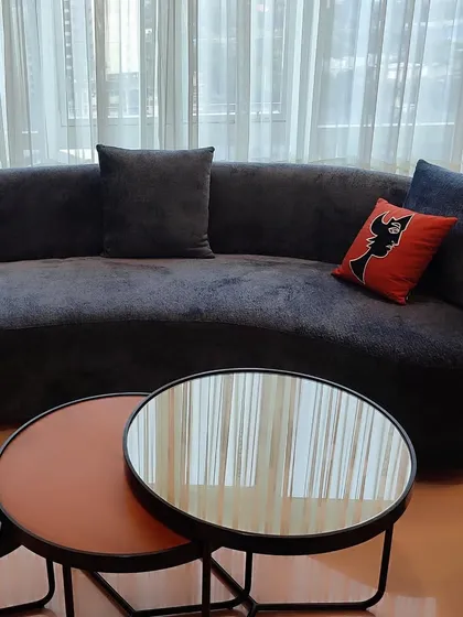 A gracefully curved sofa upholstered in a deep, luxurious black fabric anchors this living space. The fabric's subtle texture adds depth and sophistication, while a pop of color from a patterned cushion adds a playful touch.