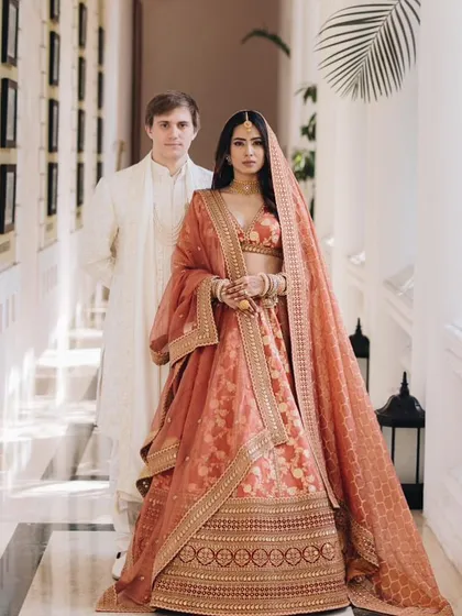 Proving that you don't have to wear red to be a stunning bride. For this couple, we chose a gorgeous rust Sabyasachi lehenga and coordinated the groom's look in a complementary ivory, creating a regal and modern aesthetic for their daytime ceremony.