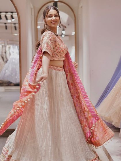 Celebrate life’s precious moments in this vibrant lehenga. The mix of a cream skirt with a pink and orange bandhani-style dupatta is pure joy.