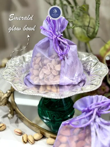 The Emerald Glow Bowl, seen here with a 'potli' of pistachios. This silver-coated bowl with an emerald green base is a perfect blend of tradition and luxury.