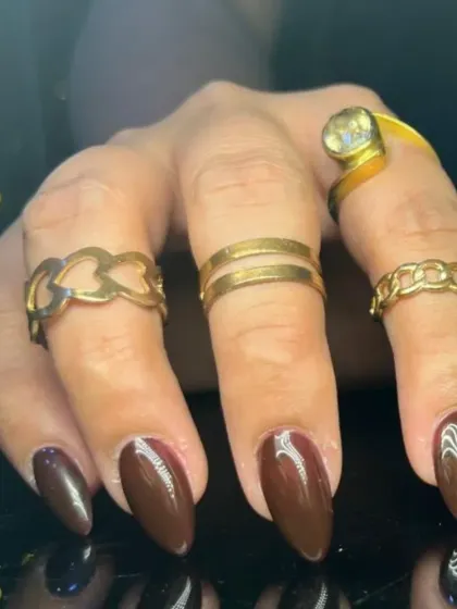 A rich and glossy dark brown manicure on almond-shaped nails, perfect for an autumn look.