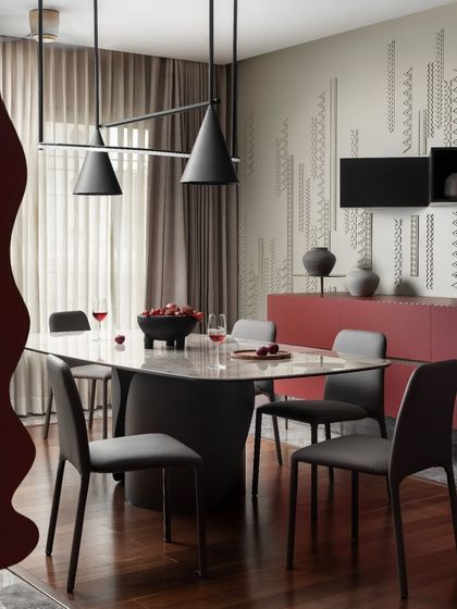 The dining area in Scarlet Horizon is an artfully curated space. We chose a sculptural dining table and simple chairs to let the bold red sideboard and custom wall detailing stand out. The minimalist pendant lights ensure the focus remains on the room's vibrant colors and textures.
